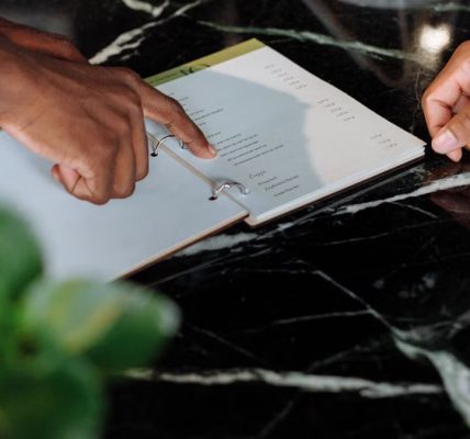 Hands pointing at menu on black marble counter inside a shop.