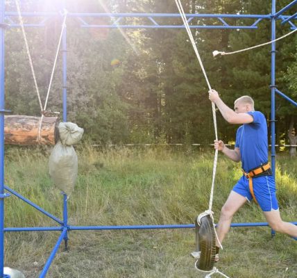 Man mastering an outdoor obstacle course with ropes and tires, showcasing strength and agility.