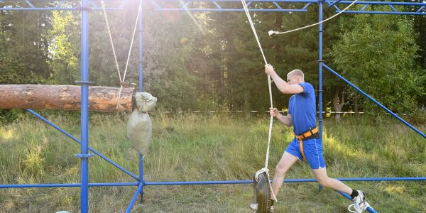 Man mastering an outdoor obstacle course with ropes and tires, showcasing strength and agility.